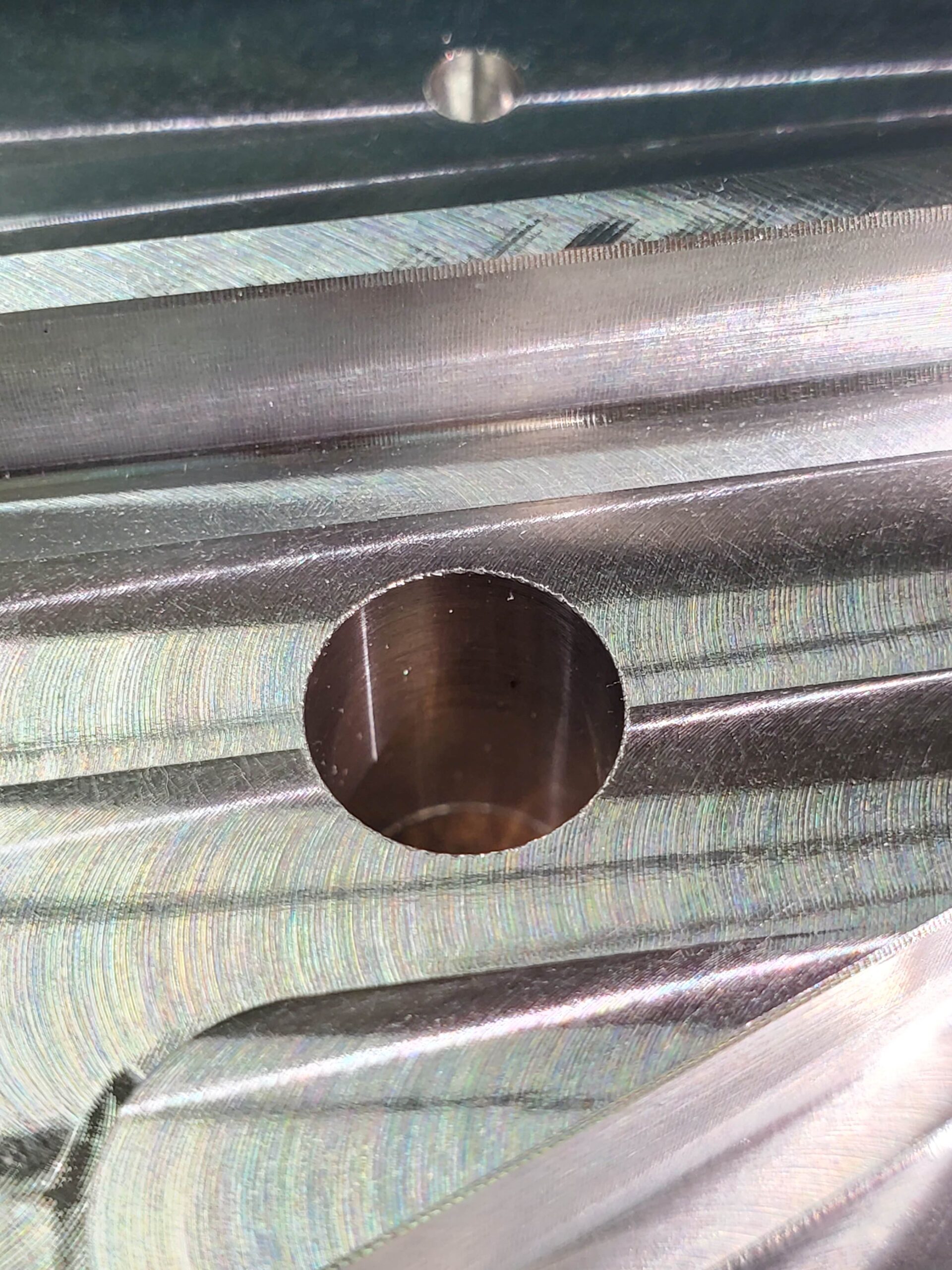 Close-up of a metallic surface with concentric ridges and a central circular hole, showing detailed machining work.